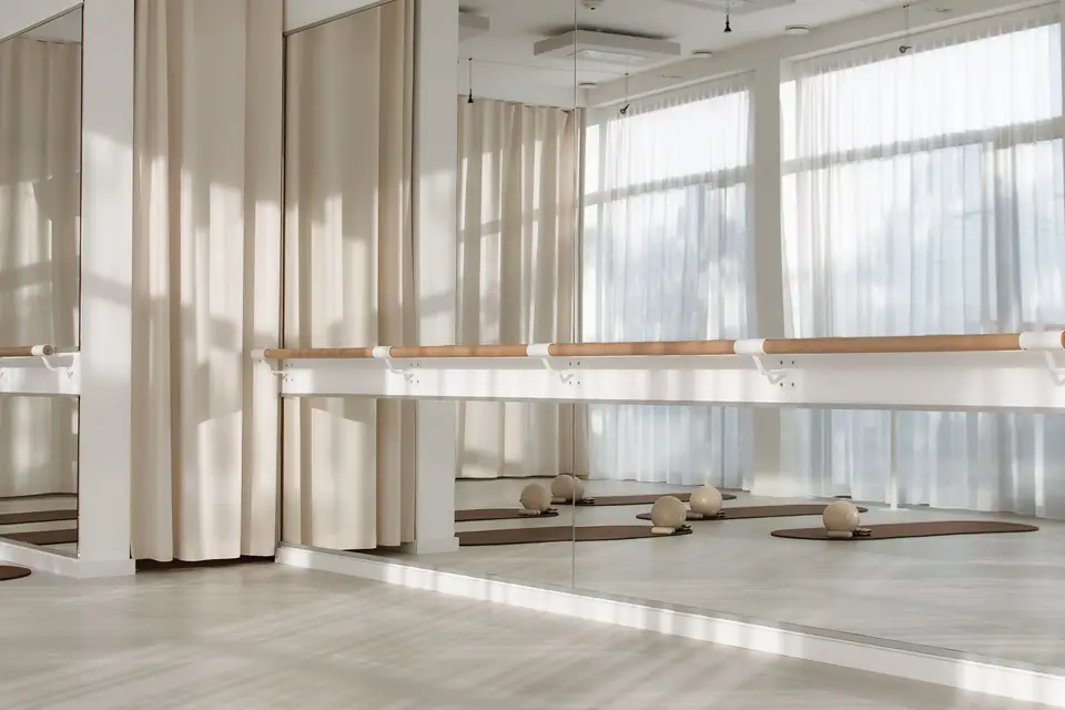 Fensterfront mit Ballettstange und Spiegel im MÉ·US Studio, Morgenlicht durch die Vorhänge
