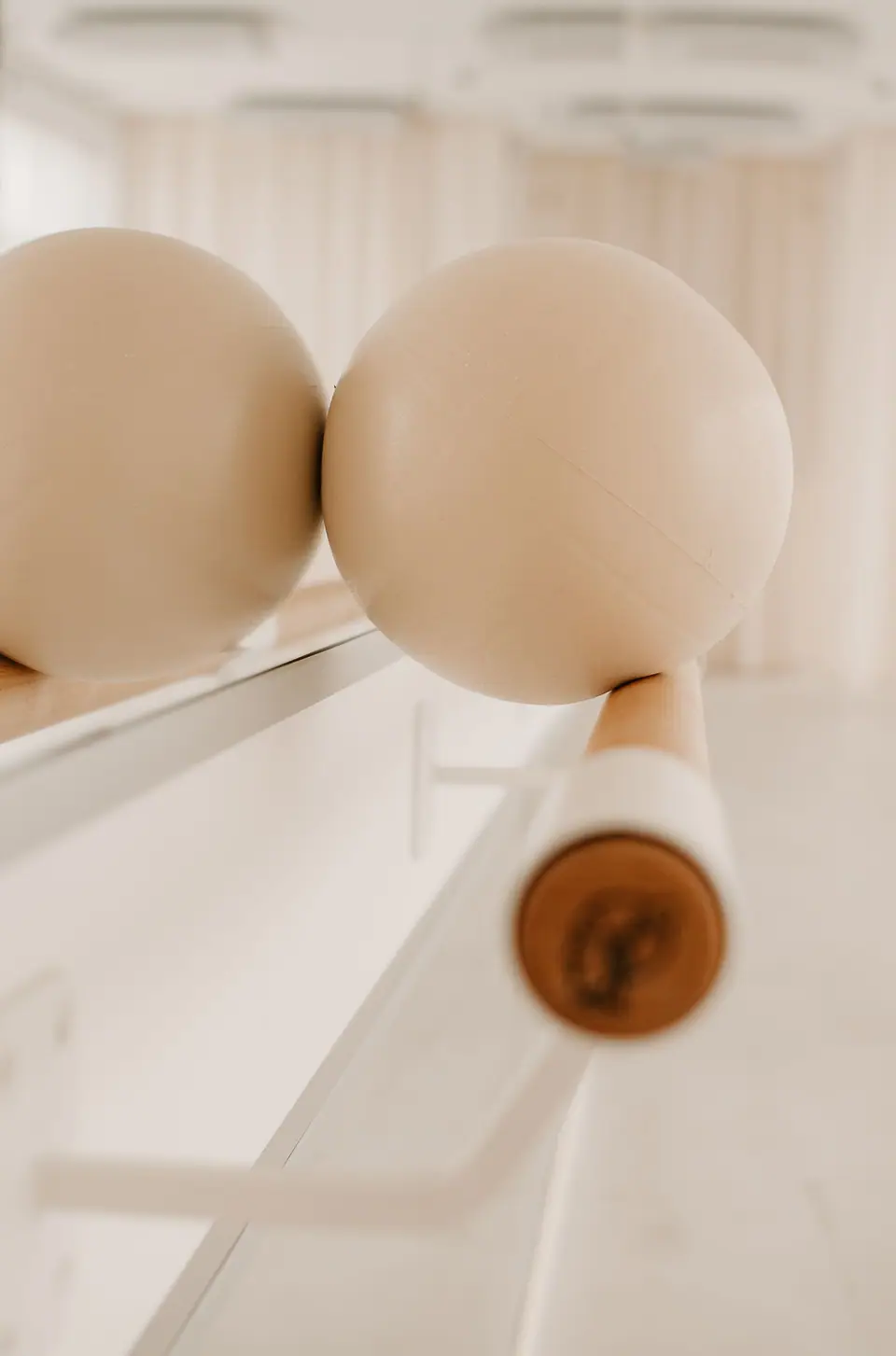 Zwei Pilates-Bälle liegen auf der Ballettstange im warmen Licht des Studios