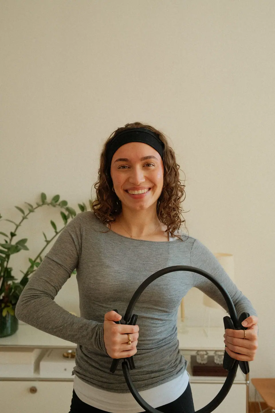 Lea, Trainerin bei MÉ·US, hält lächelnd einen Pilates-Ring im Studio