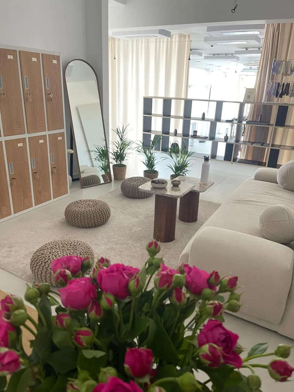 Lounge und Umkleide des MÉ·US Studios mit Sofa, Spinden und Blumen