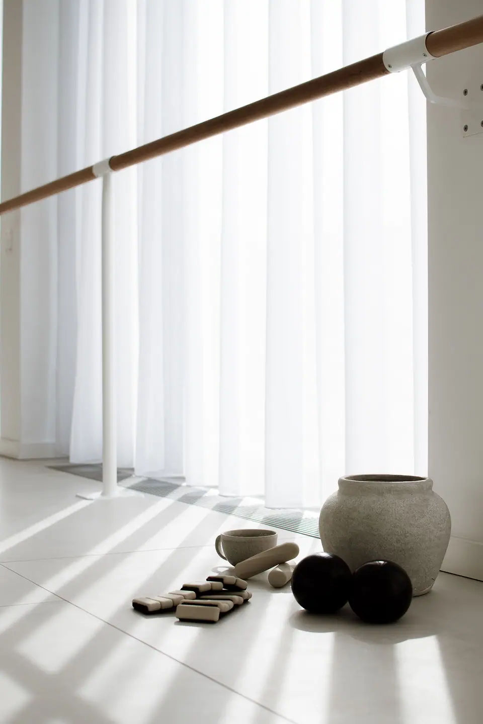 Pilates-Bälle, Gewichte und Tonvase im Sonnenlicht am Fenster des Studios