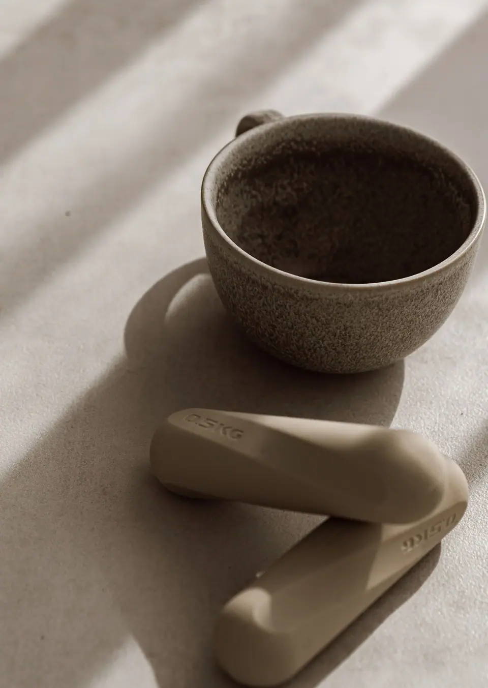Tasse und Pilates-Griffe im Licht, ein ruhiger Moment im MÉ·US Studio