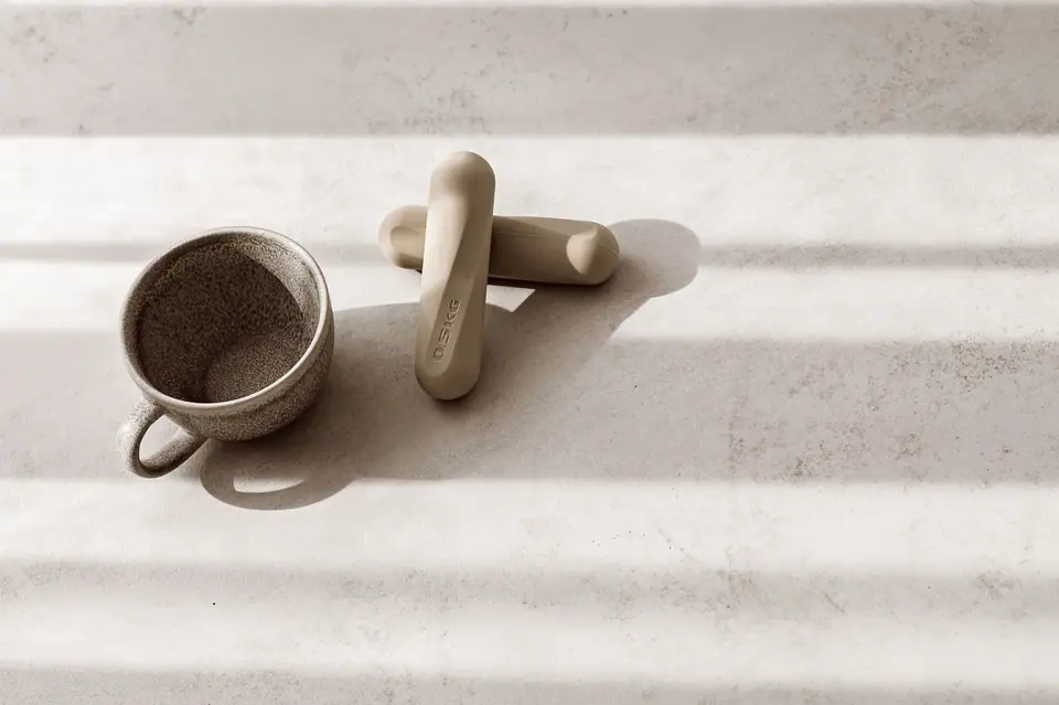 Keramiktasse und Pilates-Griffe auf hellem Boden im Streiflicht, MÉ·US Studio Heidelberg