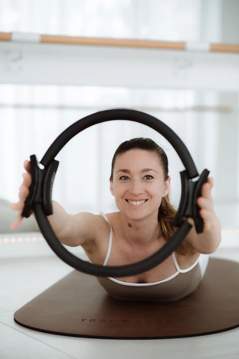 Anastasija Berg hält lächelnd den Pilates-Ring, Pilates Mat & Props im MÉ·US Studio