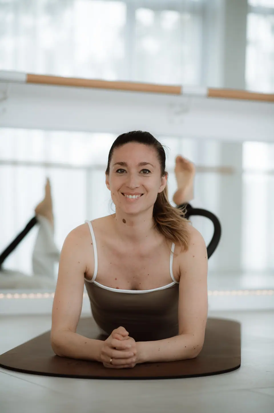 Anastasija Berg in Bauchlage auf der Matte, hinter ihr der Pilates-Ring