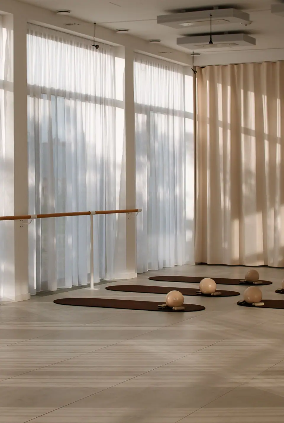 Der helle Trainingsraum von MÉ·US mit Fensterfront, Ballettstange und vorbereiteten Matten